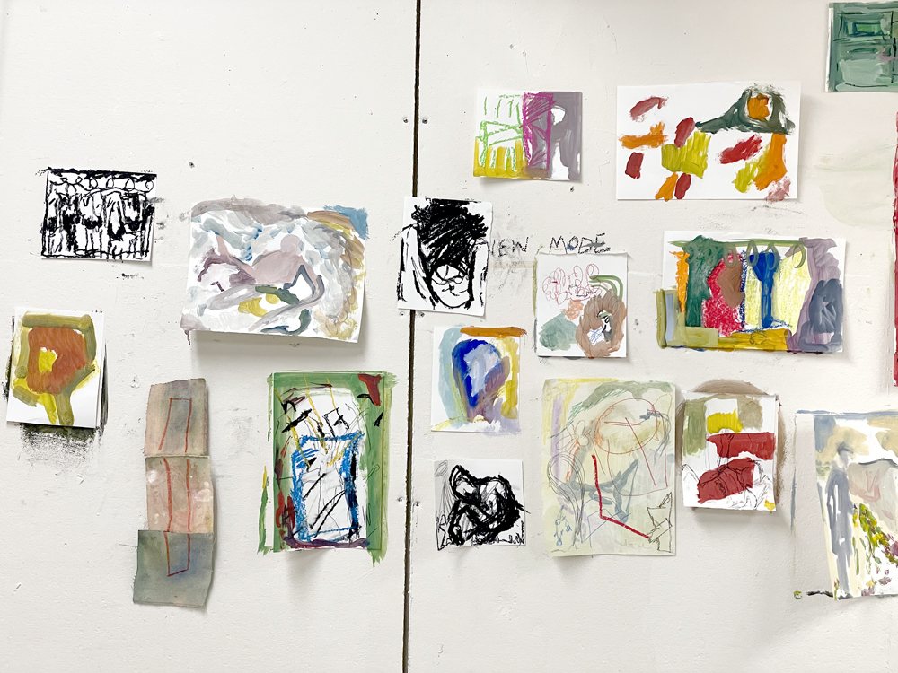 A studio wall covered in small painted and drawn studies, pinned up in a grid.